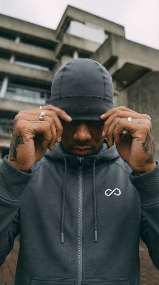 Homme portant un bonnet gris minimaliste et un hoodie zippé dans un décor urbain