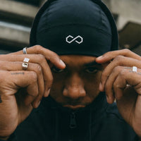 Homme portant un bonnet noir sport avec logo blanc et sweat à capuche, style urbain