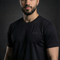 Homme portant un t-shirt noir minimaliste, logo discret, mode sport lifestyle.