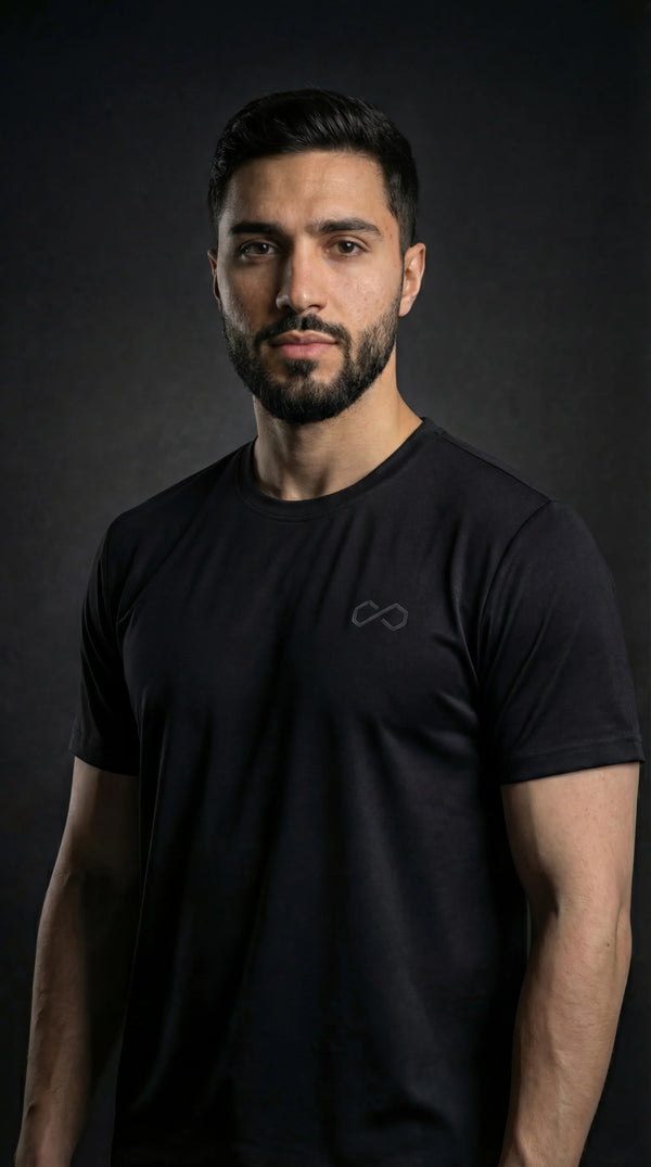 Homme portant un t-shirt noir minimaliste, logo discret, mode sport lifestyle.
