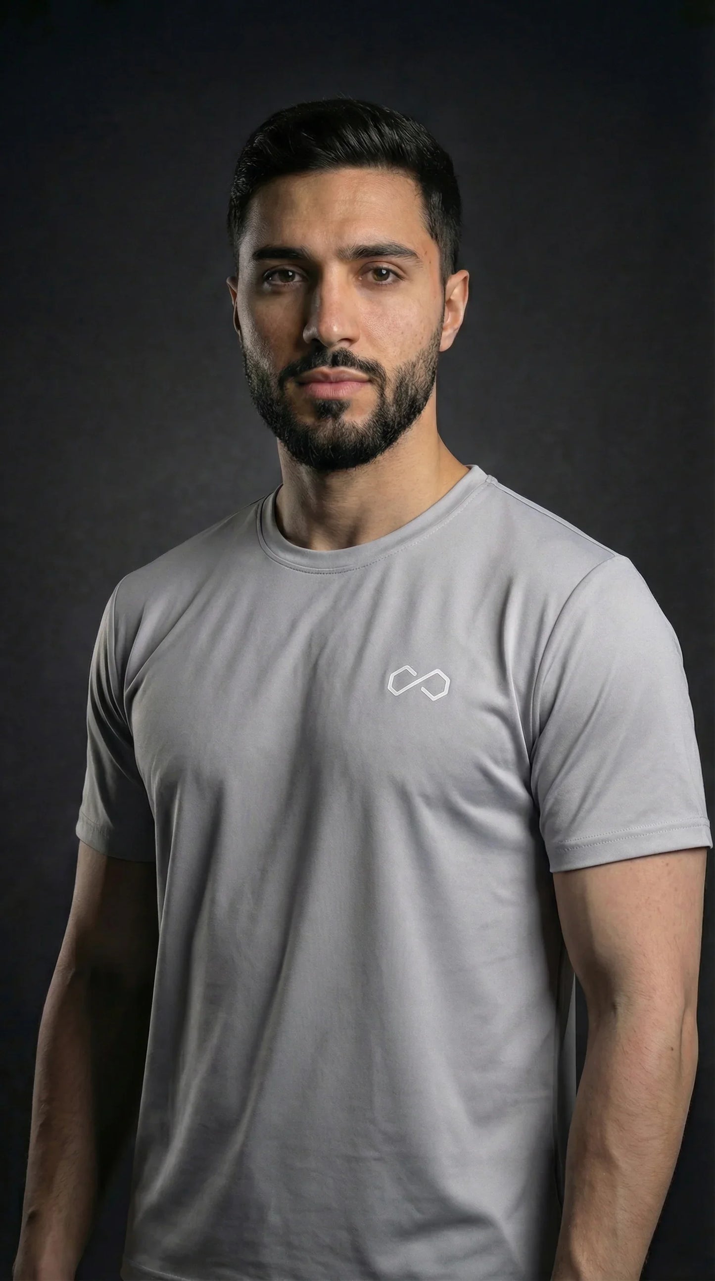 Homme portant un t-shirt sport gris à col rond, logo minimaliste blanc sur la poitrine.