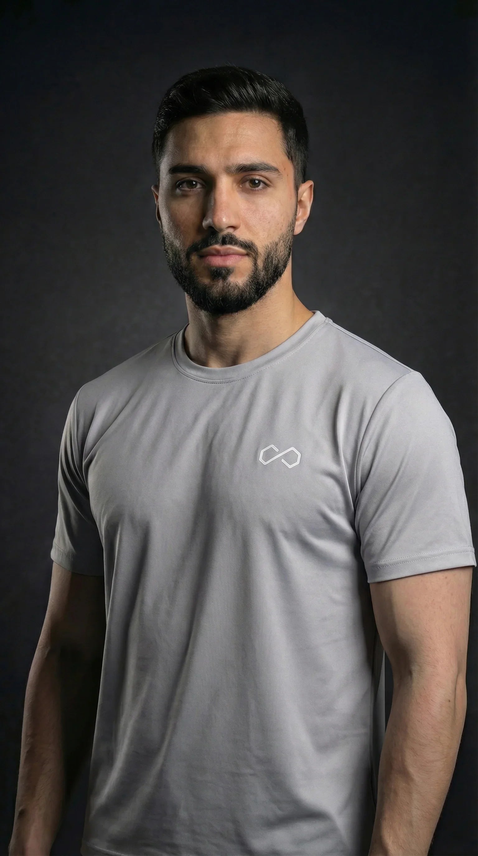 Homme portant un t-shirt sport gris à col rond, logo minimaliste blanc sur la poitrine.
