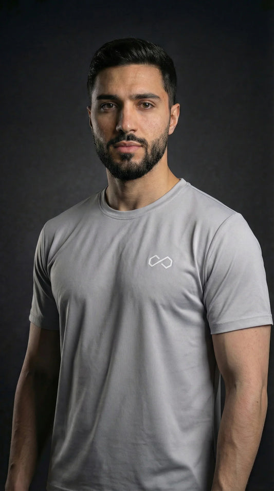 Homme portant un t-shirt sport gris à col rond, logo minimaliste blanc sur la poitrine.